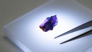 A close-up view of a tiny, reddish-orange kyawthuite crystal, the only confirmed natural specimen of this mineral species in existence.