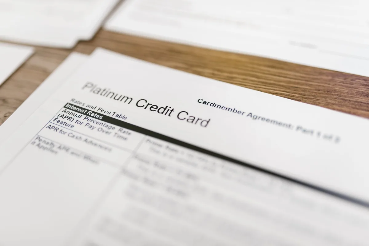 Persona che guarda il conto della carta di credito con preoccupazione, circondato da bollette