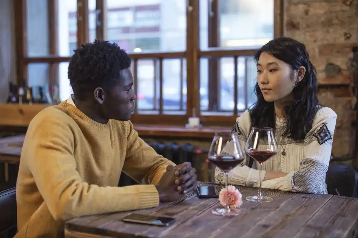 A woman and man on a date; she looks unimpressed while he speaks.