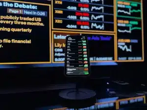 A child's hand interacting with a digital investment interface showing stock charts and savings growth on a screen