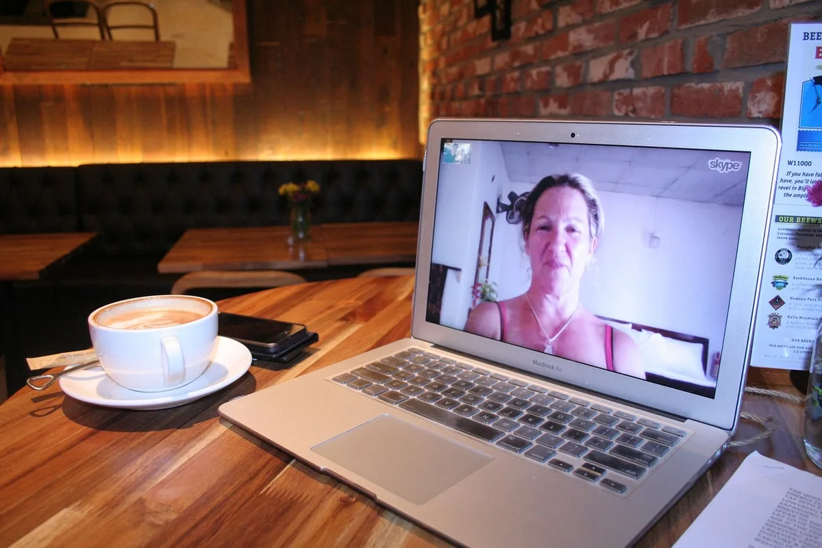 Two people talking across a small table, faces turned away to keep anonymity