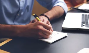 Two anonymous hands on opposite sides of a table with a folded note between them