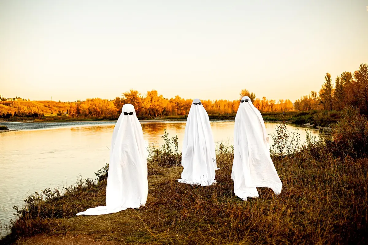 Silhouetted friends in Halloween costumes at a neighborhood block party under string lights
