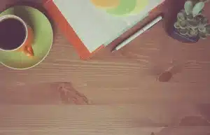 Hands exchanging financial documents and laptop on a café table