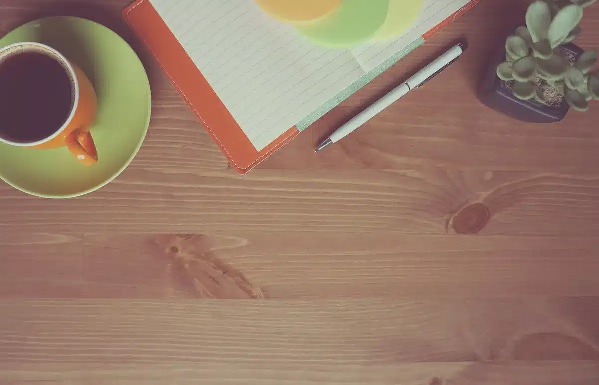 Hands exchanging financial documents and laptop on a café table