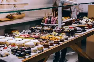 Glazed donut in a display case with a small anonymous rodent silhouette nearby in a shopping mall