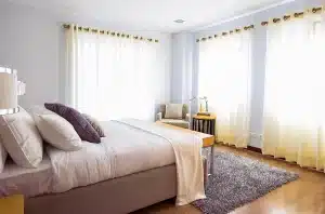 Silhouetted hands reaching on a rumpled bed with condoms and a testing kit on the bedside table