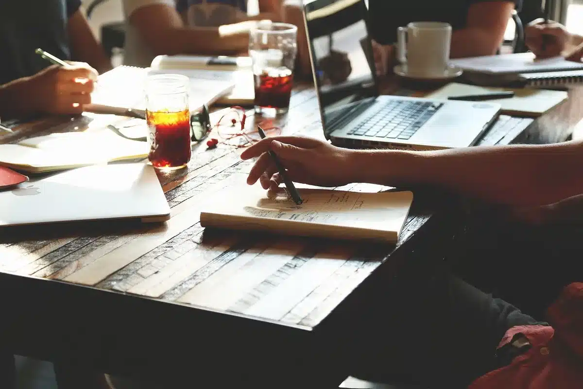 Anonymous couple planning together with a notebook and calendar on a table