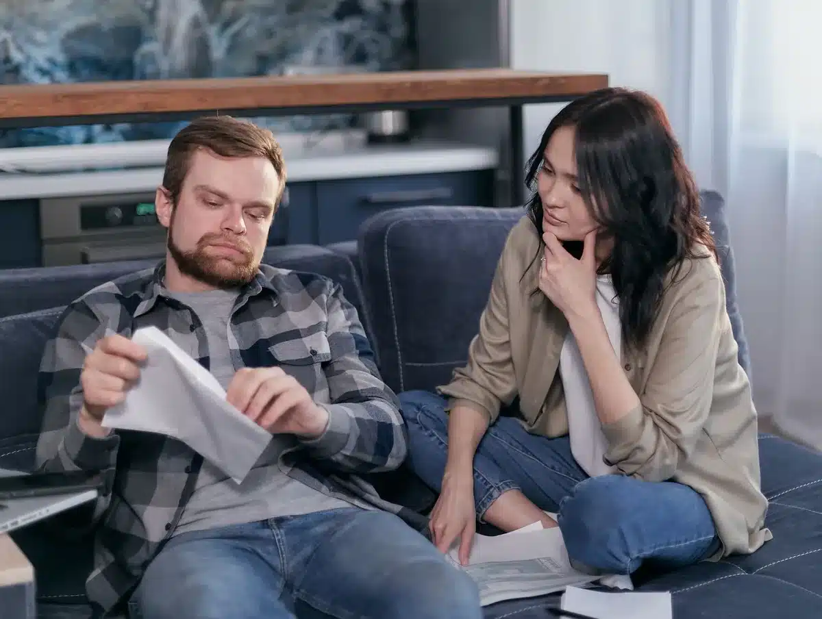 Person looking stressed over bills on a table, hands on head
